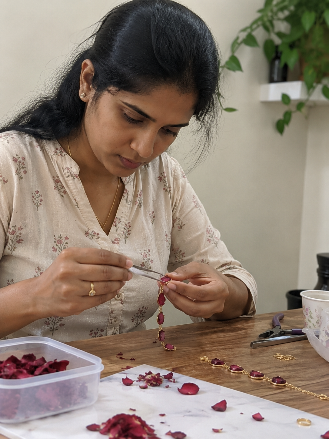 An Indian artisan's hands setting tiny flower petals into a resin pendant