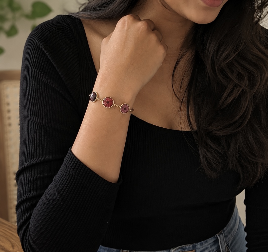 A wrist wearing a silver bracelet with a preserved-flower resin charm